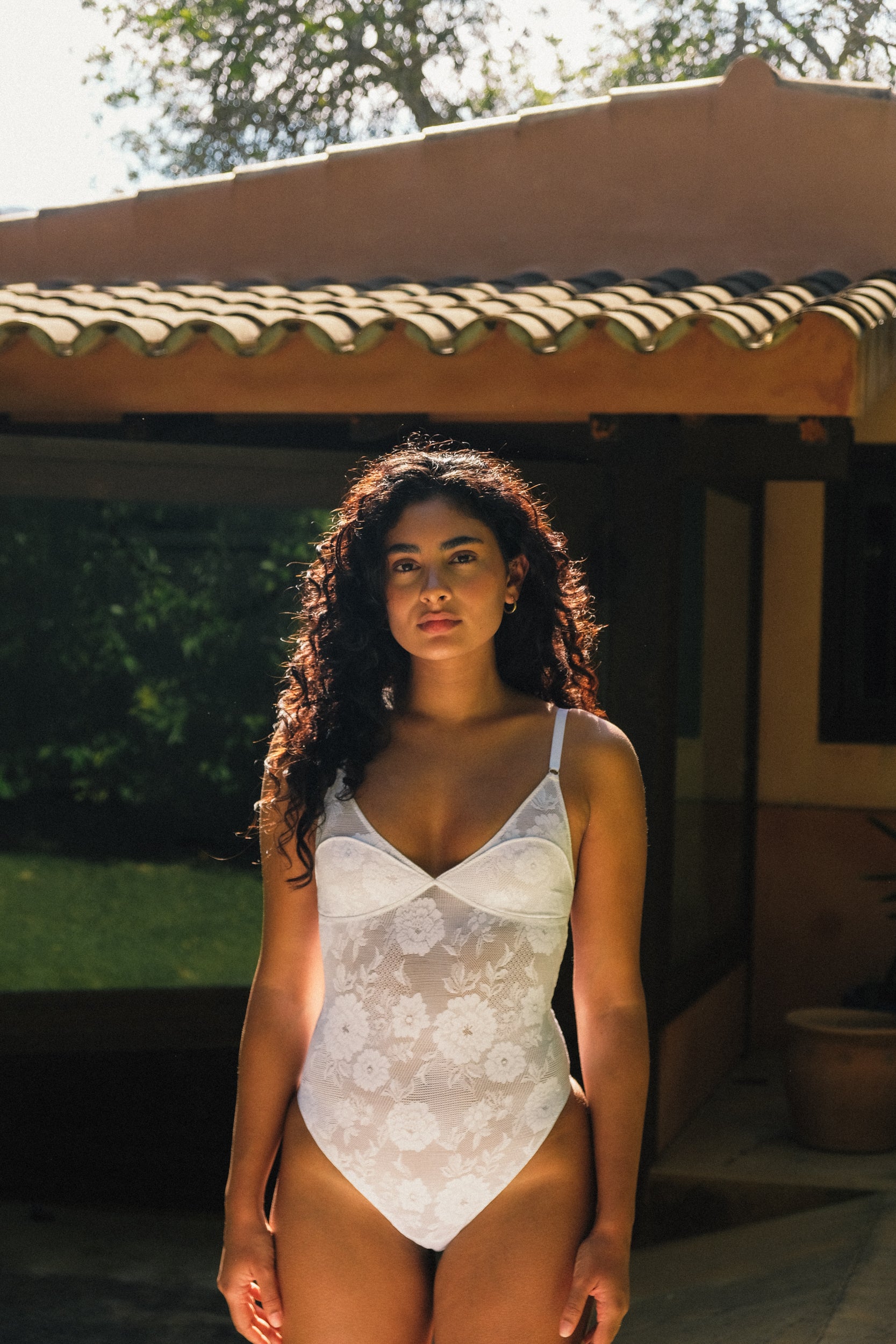 model met donker haar in wit kanten lingerie bodysuit