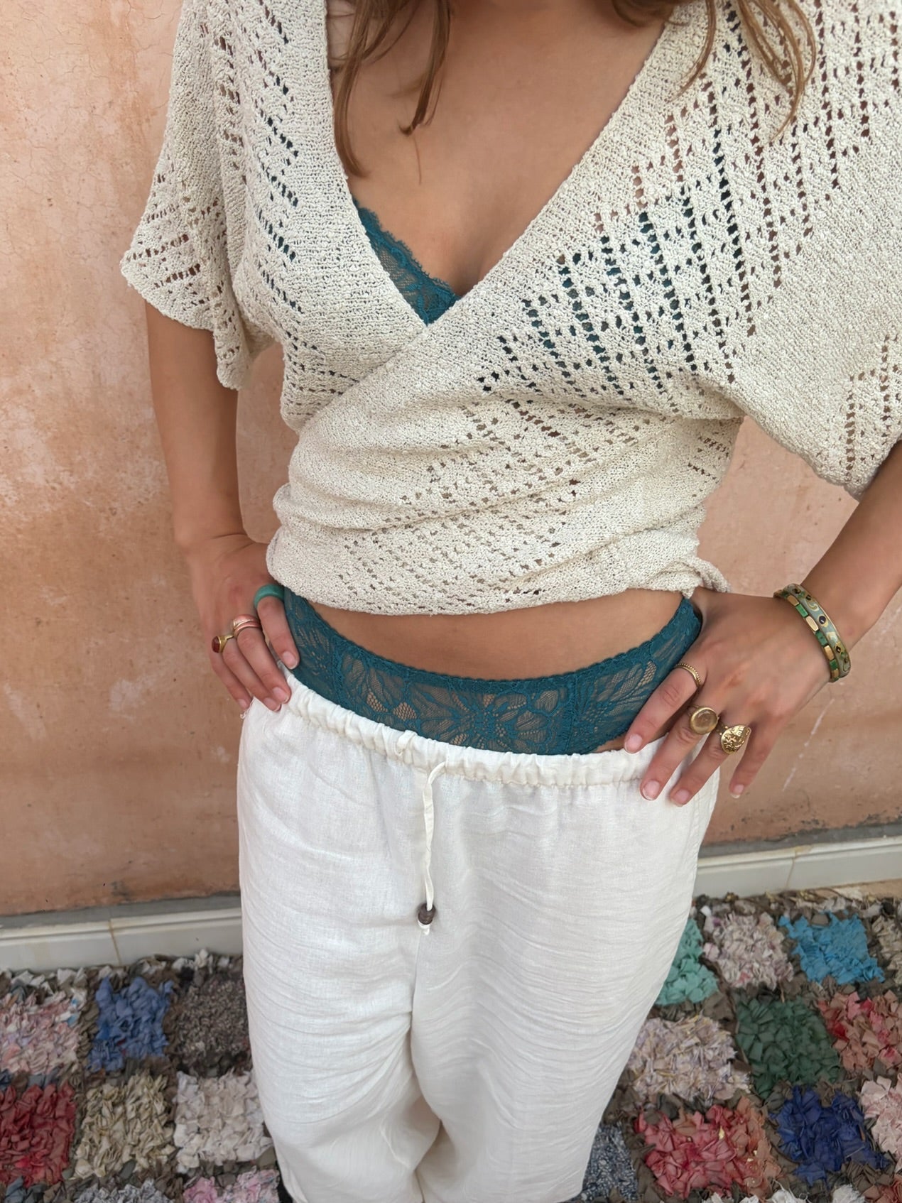 meisje met gehaakt overslag top en witte linnen broek met blauwe lingerie als details