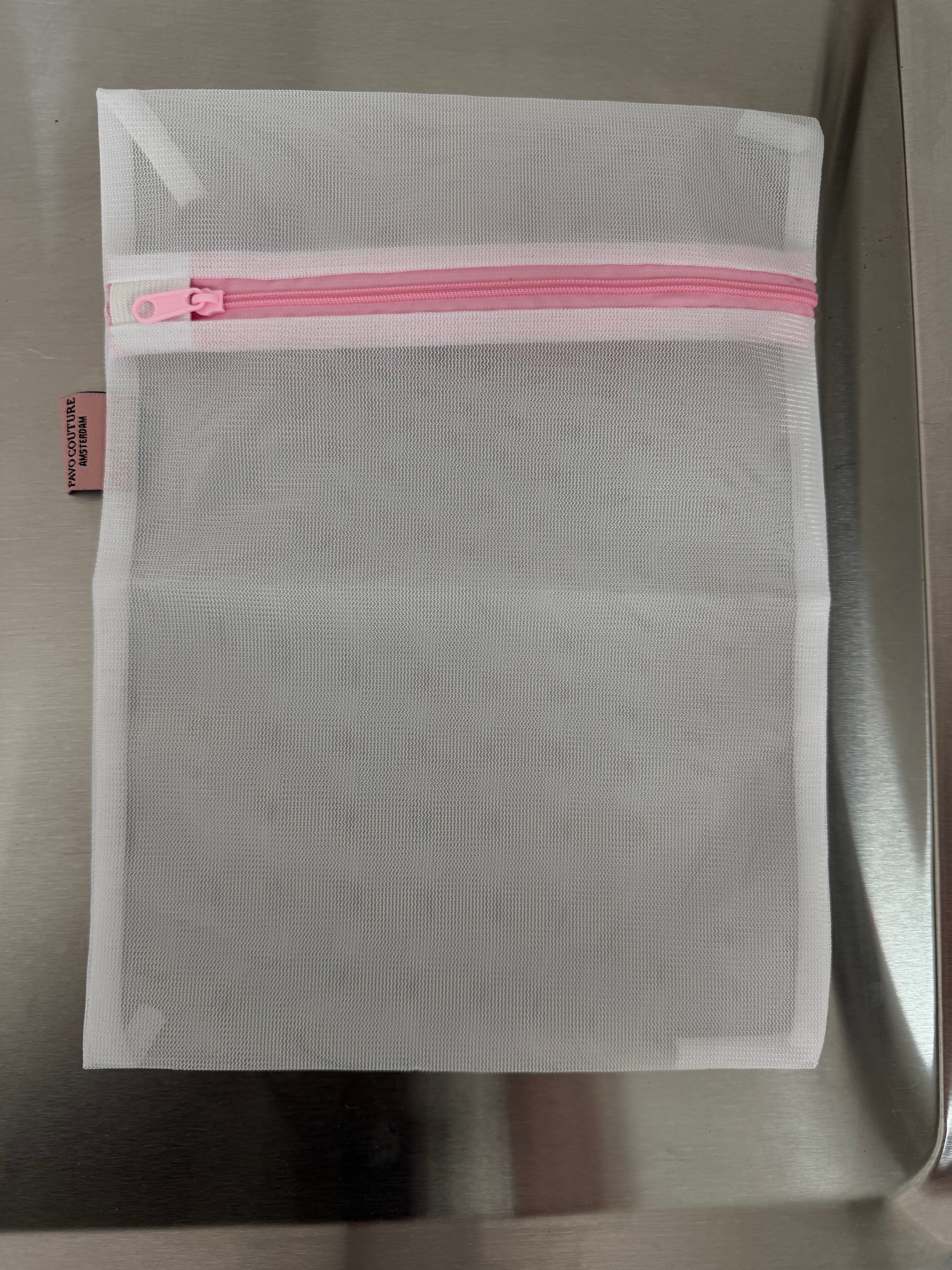 een mesh wit lingerie zakje voor de was met roze rits
